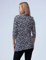 Blusa azul con estampado de círculos negros, de tejido texturado con escote en V descentrado y aplique de aro metálico.