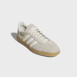 Championes Adidas Handball Spezial de ante vacuno en color beige, con las clásicas tres tiras laterales en blanco, suela de goma color caramelo y detalles dorados con el nombre del modelo en el lateral.