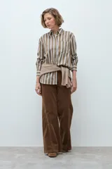 Camisa de corte clásico con estampado de rayas verticales en tonos khaki, blanco y azul. Presenta cuello camisero, cierre frontal con botones, bolsillo en el pecho y mangas largas con puños abotonados.