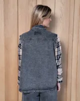 Chaleco de gabardina color tostado, con cuello camisero, cierre frontal con botones metálicos y dos bolsillos frontales con solapa.