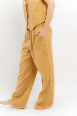 Pantalón de algodón color verde oliva, de corte recto y tiro alto con elástico en la parte trasera de la cintura. Presenta bolsillos laterales y un bolsillo trasero con tapa.