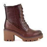 Bota de caña media color marrón con cordones y cierre lateral. La parte superior de la caña es de cuero con textura de cocodrilo. Tiene suela track color caramelo y taco cuadrado.