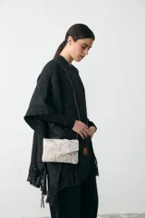 Bandolera pequeña de diseño minimalista en color plateado metalizado con acabado texturizado. Cuenta con cierre de solapa y cordón de cuero fino extraíble que permite su uso como sobre.