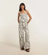 Pantalón wide leg de sarga con estampado animal print dálmata, trabillas en la cintura, cierre con botón y cremallera, y bolsillos delanteros y traseros.