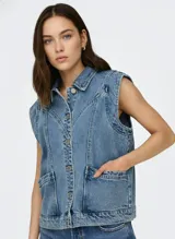 Chaleco largo de denim color azul medio, con cuello camisero, cierre frontal de botones metálicos y bolsillos de parche en la parte delantera.