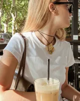 Collar con dije grande de bronce con forma orgánica y textura rugosa, suspendido de un cordón negro. Incluye cordones intercambiables.