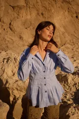 Camisa celeste de silueta entallada con diseño estilo corset, alforzas estructuradas en el torso, cuello clásico, botones oscuros y mangas largas abullonadas.