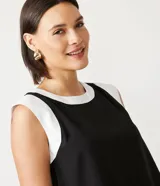 Blusa negra de viscosa con escote redondo y sisa contrastante en color blanco. Sin estampado.