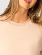 Buzo de punto color rosa, con cuello redondo y detalle de tejido crochet en el escote. Presenta mangas largas y un corte clásico con caída suave.