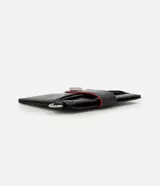 Billetera compacta Satinato de poliuretano color negro, con solapa frontal con botón a presión, detalles en rojo y argolla lateral metálica.