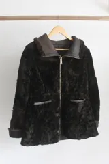 Campera reversible de cuero genuino napalán color marrón oscuro, con cuello, solapas, bolsillos frontales y detalles en corderito negro. Cierre frontal con cremallera.