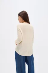 Sweater de tejido de punto fino en color blanco, con cuello redondo a la base y mangas largas de corte holgado.