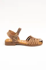 Sandalias cangrejeras de cuero color marrón, con diseño de tiras cruzadas en la parte delantera, suela plana y tira ajustable en el tobillo con hebilla metálica.
