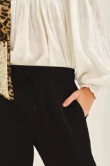 Pantalon estilo babucha color negro, con cintura elastizada y cordón de ajuste, bolsillos diagonales frontales y puños en los tobillos.