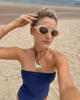 Collar artesanal con dije de bronce macizo en forma orgánica irregular, similar a una concha marina, suspendido de un cordón de seda natural negro. El diseño permite diversas formas de uso, ya sea ajustado al cuello o largo.