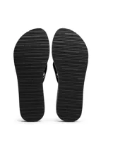 Ojotas de mujer con plataforma tipo cuña, suela EVA dentada y tiras de textil trenzado a rayas negras y blancas. Presentan una insignia con monograma TH en la tira del dedo.