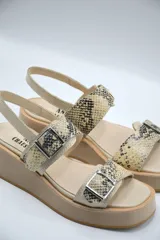 Sandalia de plataforma color beige claro, con dos tiras anchas con estampado de piel de serpiente (pitón) y hebillas metálicas.