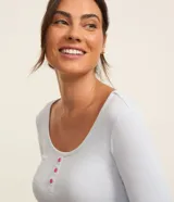 Conjunto de pijama largo de poliéster y elastano. Incluye una blusa celeste de manga larga con botones en el cuello y un pantalón de corte recto con estampado de cuadros en tonos blanco, rosa y gris.