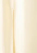 Vestido midi de tejido satinado en color beige claro, con escote halter en pico, detalles fruncidos en el pecho, tirantes finos y abertura lateral.