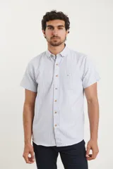 Camisa de manga corta a rayas verticales blancas y celestes, con cuello abotonado y bolsillo en el pecho.