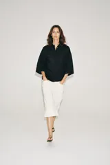 Camisa amplia confeccionada en hilatura con lyocell y ramio, color celeste, con cuello solapa, manga por debajo del codo, detalle de pliegue en la espalda y cierre frontal con botones ocultos por solapa.
