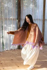 Ruana tejida con diseño de espiga en tonos lila y tostado, con terminación de flecos en color lila en todo el borde.