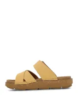 Sandalia de color amarillo claro con diseño de doble tira cruzada en el empeine, una de ellas ajustable con hebilla grande. Suela de plataforma baja con textura tipo corcho.