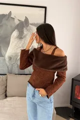 Sweater tejido de punto con lurex color cobre, diseño off-the-shoulder con breteles y detalle de franja de piel sintética en color marrón oscuro. Posee mangas largas y corte ajustado.