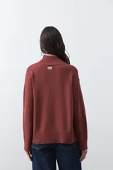 Polera de tejido liviano en color negro, con cuello alto, mangas largas y corte relajado. Presenta un diseño minimalista con recortes laterales que aportan estructura a la prenda.