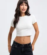 Blusa cropped de cuello redondo y manga corta, confeccionada en algodón con elastano. Presenta un diseño ajustado al cuerpo y acabado liso.