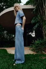 Jeans de tiro alto con pernera ancha y costuras marcadas en el frente. Presenta cintura elástica en la parte posterior, cierre frontal con cremallera y botón, bolsillos delanteros y bolsillos de plastrón en la parte trasera.