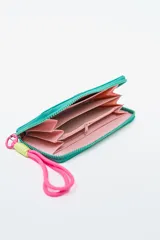 Billetera rectangular con cierre, color celeste pálido, con parche frontal negro que lleva las letras "CNJ" en relieve. Incluye un llavero de muñequera con cordón trenzado en rosa fuerte y verde lima.