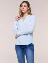 Blusa celeste fluida de viscosa, con escote en V y cuello mao, mangas largas y pliegue central en el delantero.