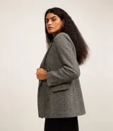 Blazer de tweed gris con diseño de espiga, doble botonadura, solapas de muesca, bolsillos cargo frontales y corte clásico.