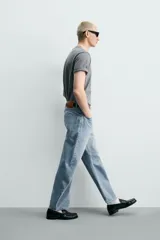 Jeans de denim de algodón en color negro con efecto lavado, corte amplio y silueta curva tipo barrel fit con pinzas en las rodillas. Presenta diseño clásico de cinco bolsillos y cierre frontal con cremallera y botón metálico.
