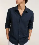 Camisa de manga larga color verde militar, confeccionada en algodón con textura maquinetada, cuello inglés y abotonado delantero. Corte comfort.