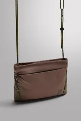 Bandolera plana de tejido técnico color marrón topo, con cierre principal y bolsillos frontales y traseros con cremallera. Incluye asa de hombro ajustable de cordón trenzado verde y marrón, con tope regulable.