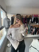 Top color crema con escote off-shoulder, mangas largas acampanadas y tejido de punto acanalado.