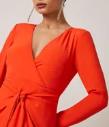 Vestido corto color naranja, confeccionado en crepé, con escote en V cruzado, mangas largas y lazo en la cintura.