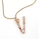 Collar dorado con cadena de eslabones y dije en forma de letra V adornado con circonitas blancas y rojas, una perla y un dije con forma de flor.