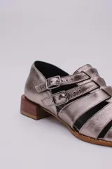 Sandalias bajas de cuero color dorado con tiras entrecruzadas y hebillas ajustables. Taco de madera.