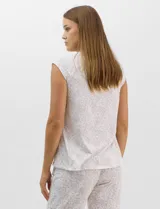 Pijama compuesto por remera sin mangas con escote redondo, botones frontales y detalle de puntilla, acompañado de un pantalón capri con cintura elástica. Presenta un estampado floral en tonos rosados sobre base gris.