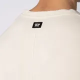 Remera oversize de lino entramado color blanco off-white, con cuello redondo, mangas cortas de hombro caído y etiqueta aplicada en el borde inferior.