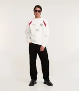 Saco deportivo boxy de algodón felpa color blanco, con cuello redondo, manga raglán larga y recortes rojos en los hombros. Presenta bordados frontales con texto "OFFICIAL NATIONAL MAJOR HARMONY", un logo circular y el número "31". Las mangas tienen un patrón de cuadros rojos y blancos.