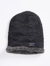 Gorro tipo beanie de punto con diseño de textura en relieve y forro interior de piel sintética gris. Incluye una etiqueta decorativa de la marca Benson & Thomas en la parte inferior.