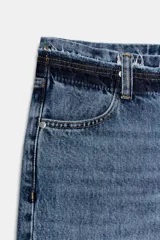 Jeans de tiro bajo y corte recto, confeccionados en denim con efecto lavado. Presentan cintura con trabillas, bolsillos delanteros y traseros, y cierre frontal con cremallera y botón.