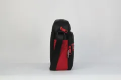 Morral deportivo NBA, de diseño compacto en color negro con detalles en rojo y azul. Cuenta con un compartimento principal con cierre, un bolsillo frontal con cierre y correa ajustable para el hombro.