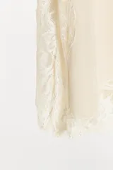 Top lencero de tirantes finos con escote en pico y aplicaciones de encaje a tono en el escote, laterales y bajo. Presenta aberturas laterales en el ruedo.