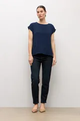 Blusa blanca con textura plumeti, de manga corta y cuello redondo.