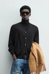 Cárdigan de punto tejido en seda, color negro, con cuello en pico, manga larga y cierre frontal de botones. Presenta acabados en rib en puños y bajo.